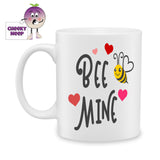White ceramic mug with a picture of a bumble bee with a white heart wing and the words "Bee mine" and four love hearts as produced by Cheekyneep.com