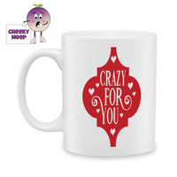 White ceramic mug with a red arabesque and inside the arabesque are the words 