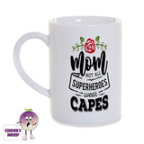 White porcelain mug with the words "Mom not all superheroes wear capes" printed in black with a red rose and green leaves on the mug as produced by Cheekyneep.com