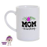 White porcelain mug with the words "Mom the heart of the family" printed in black with a pink flower and green stems on the mug as produced by Cheekyneep.com