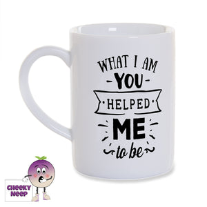 White porcelain mug with the words "What I am you helped me to be" printed on the mug in black as produced by Cheekyneep.com