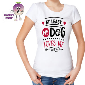 Woman wearing a white tee with the slogan "At least my dog loves me" printed on the tee. Tee as produced by Cheekyneep.com