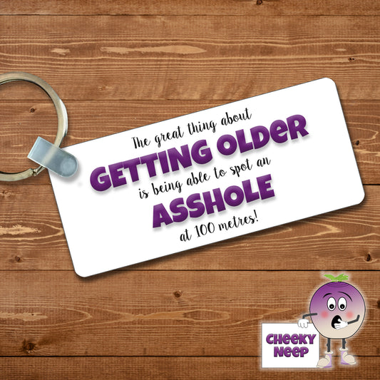 Rectangular plastic keyring with the words "The great thing about GETTING OLDER is being able to spot an ASSHOLE at 100 metres!" printed on both sides.