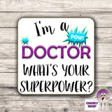 Square hardbacked coaster with the words "I'm a doctor what's your superpower?" printed on it.