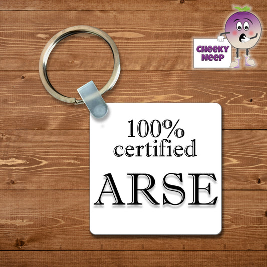 Square plastic keyring with the words "100% Certified Arse" printed on both sides.