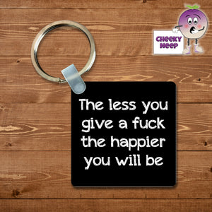 Black square keyring with the words "The less you give a fuck the happier you will be"  printed on the keyring as supplied by Cheekyneep.com